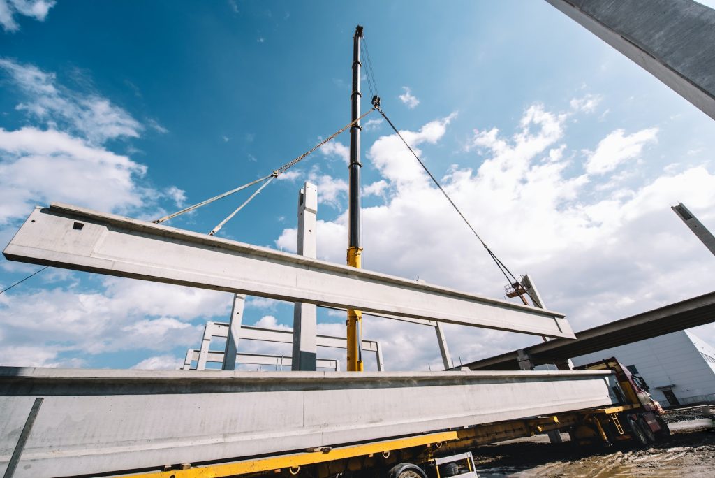 Industrial heavy duty crane lifting precast cement beams and pillars on construction site