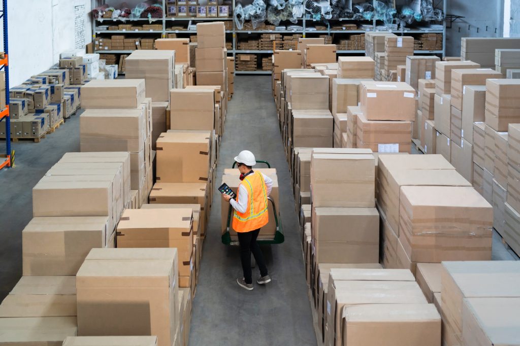 Logistic warehouse worker delivering boxes on a trolley